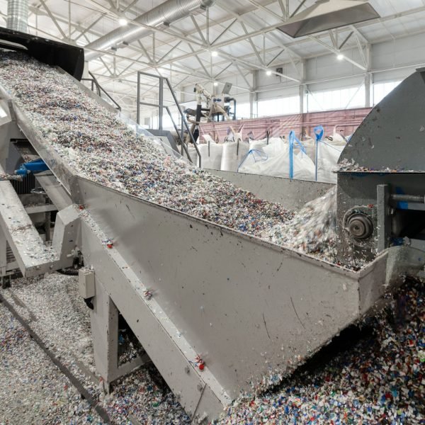 Kunststoff-Recycling: zerkleinerte Post-Consumer-Rezyklate auf Förderband
